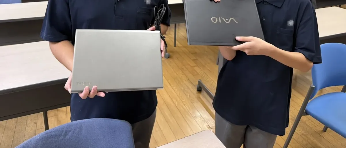 Children holding the refurbished laptops they received
